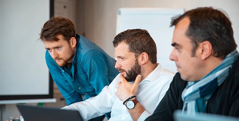 3 men discussing at a desk