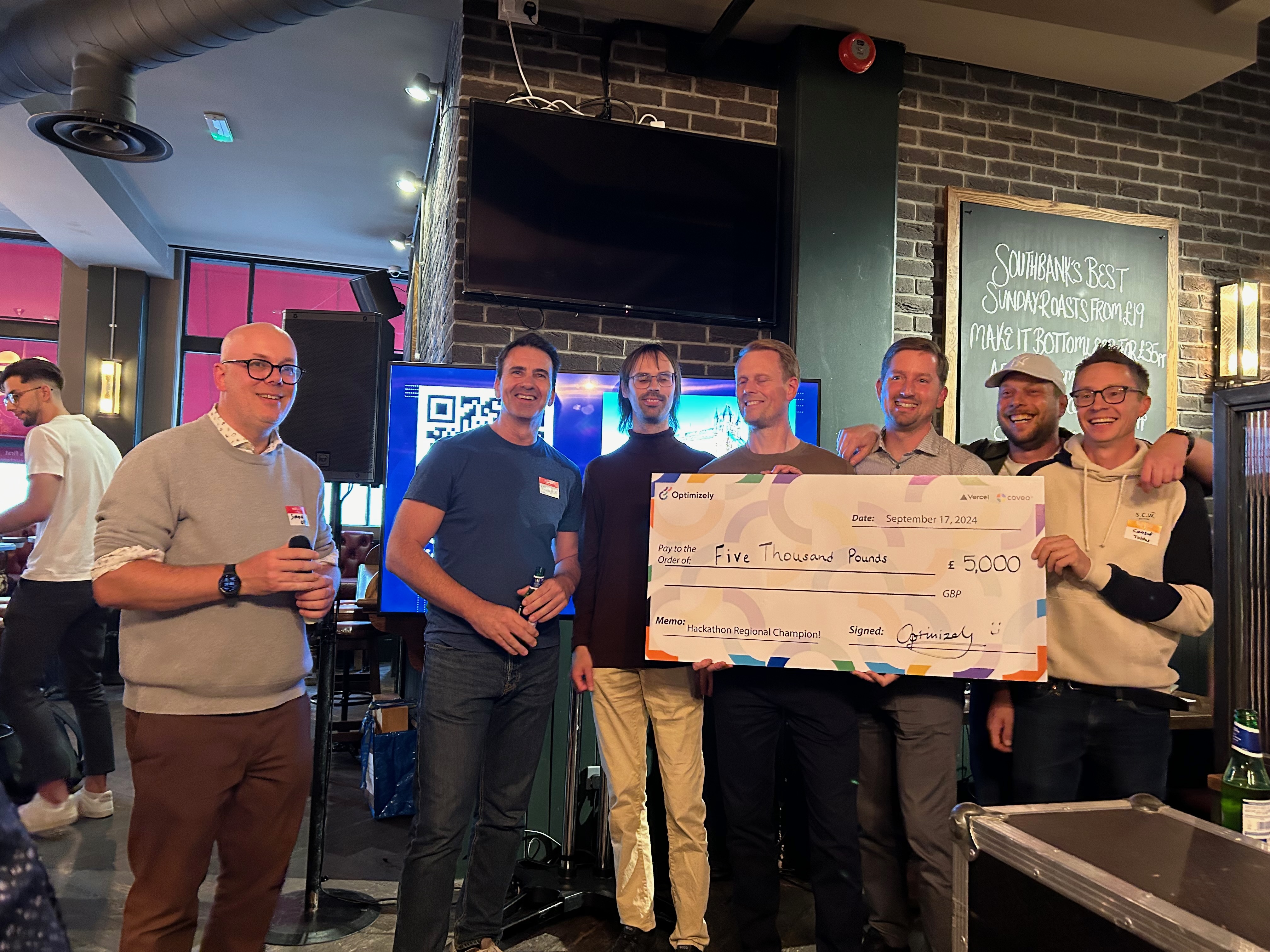 The winning team for London, Optimizely SaaS CMS hackathon 2024, holding giant check.